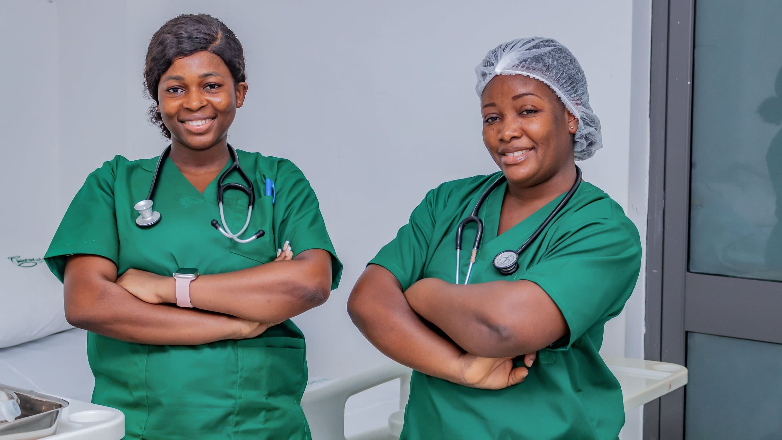 Two nurses in scrubs with stethoscopes standing in a hospital ward